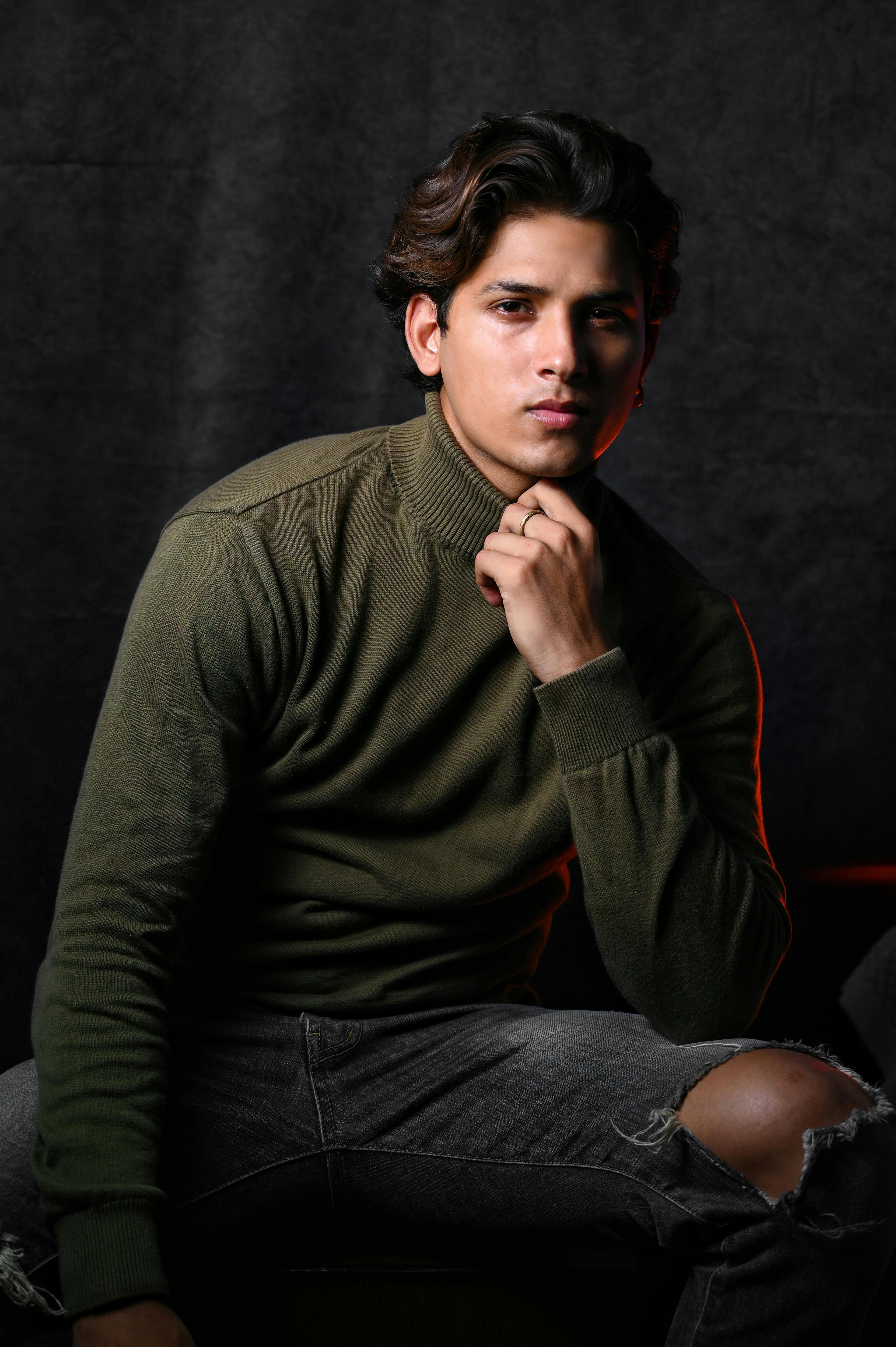 Man wearing a green sweater against a dark background